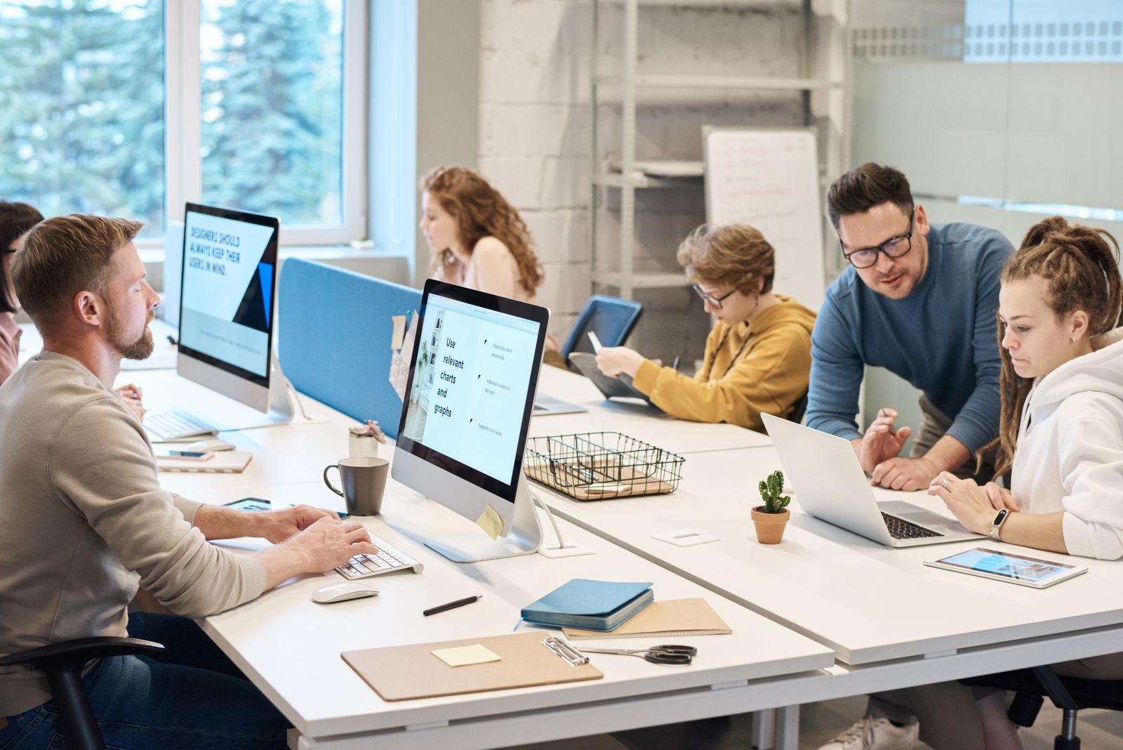 Creative team working together at computers in a bright modern studio